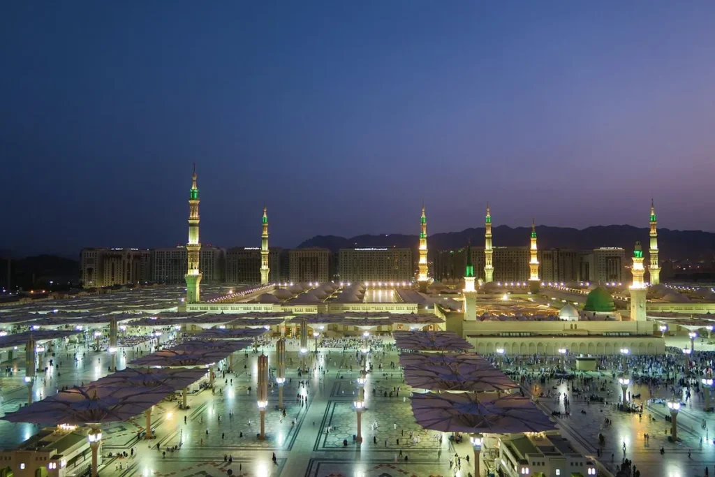 Illuminated minarets and courtyard of the Prophetβs Mosque in Madinah at dusk